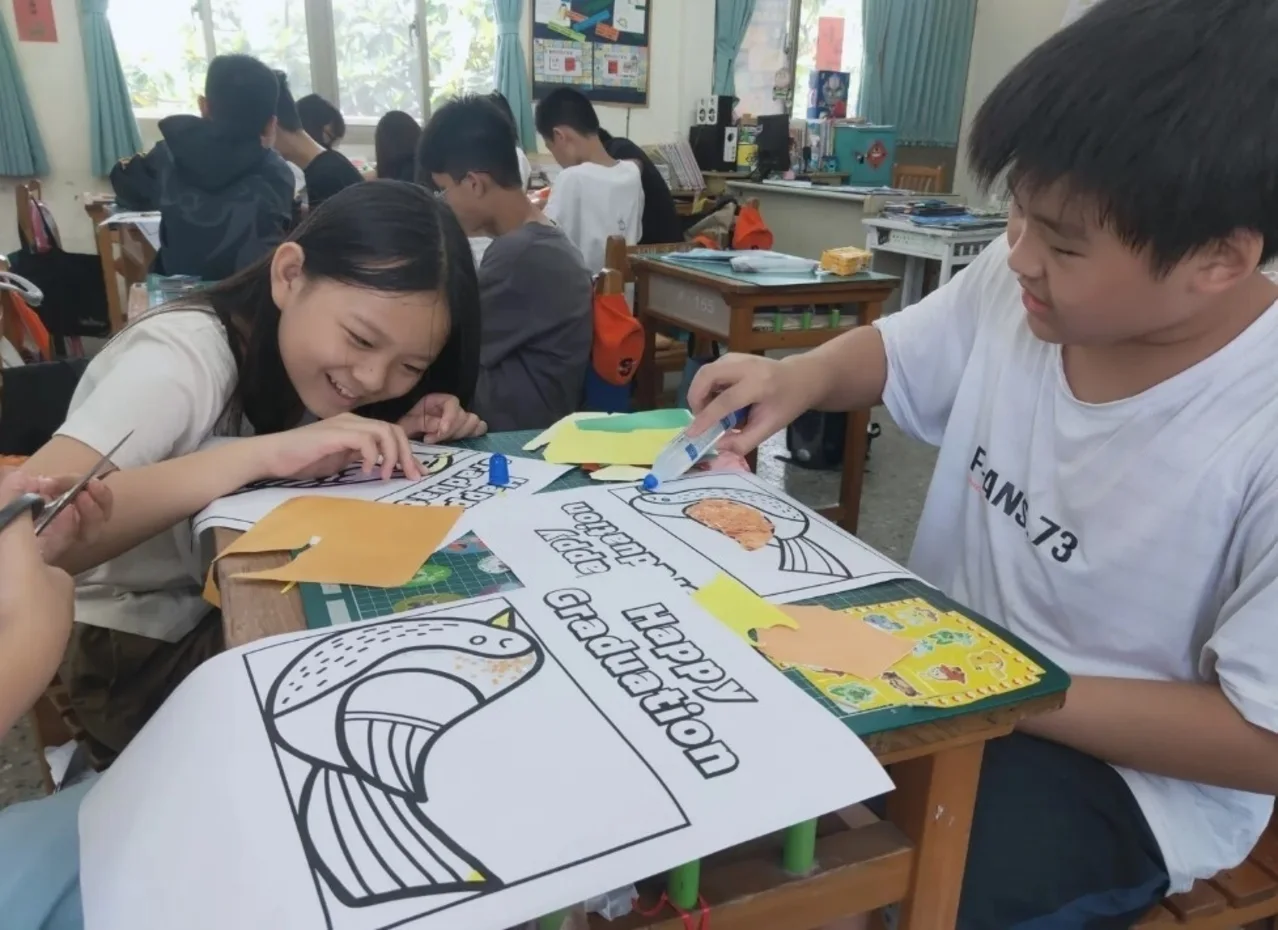 學生在課桌上剪貼紙張，共同完成圖像創作